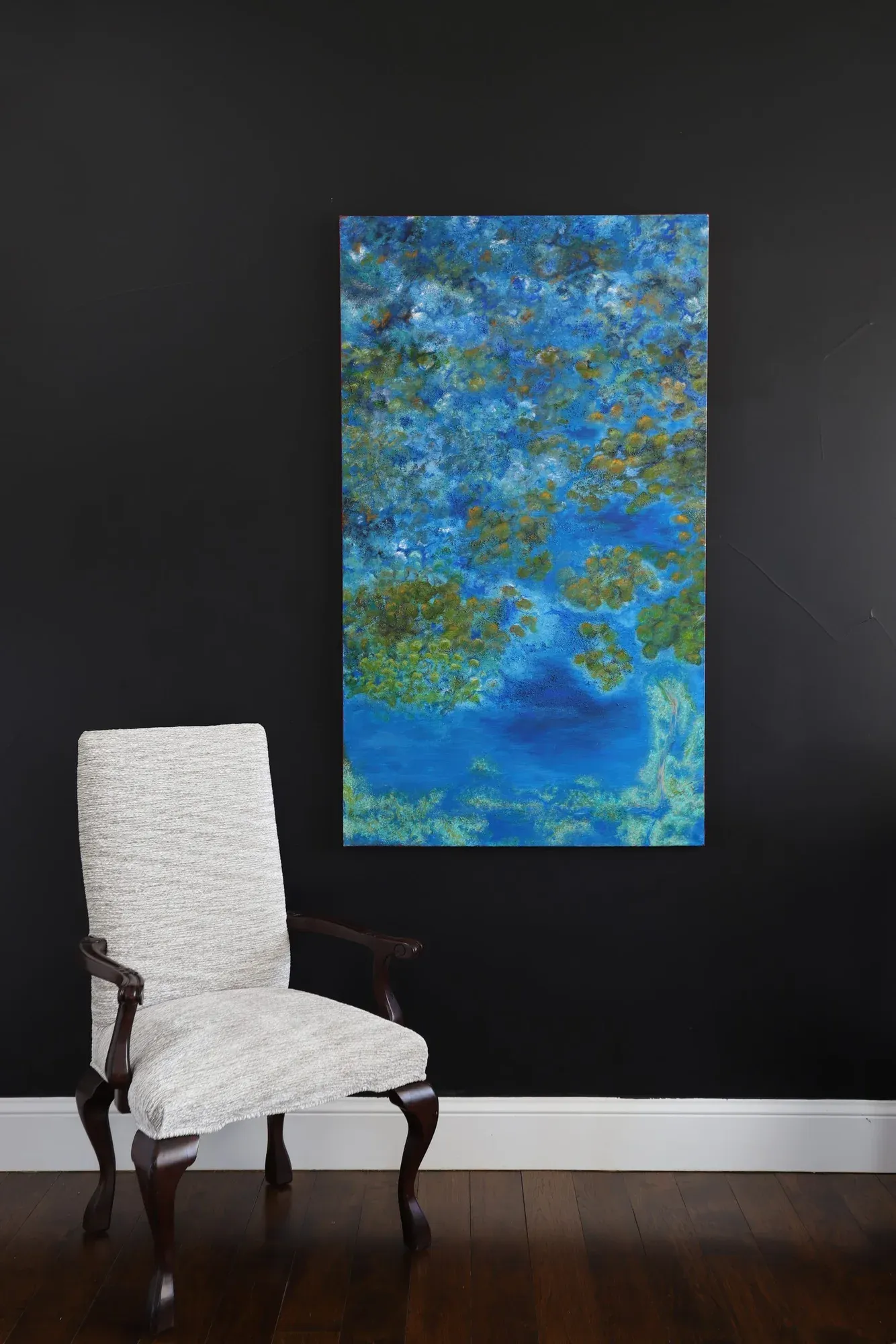 Large blue and green abstract painting beside a tufted armchair
