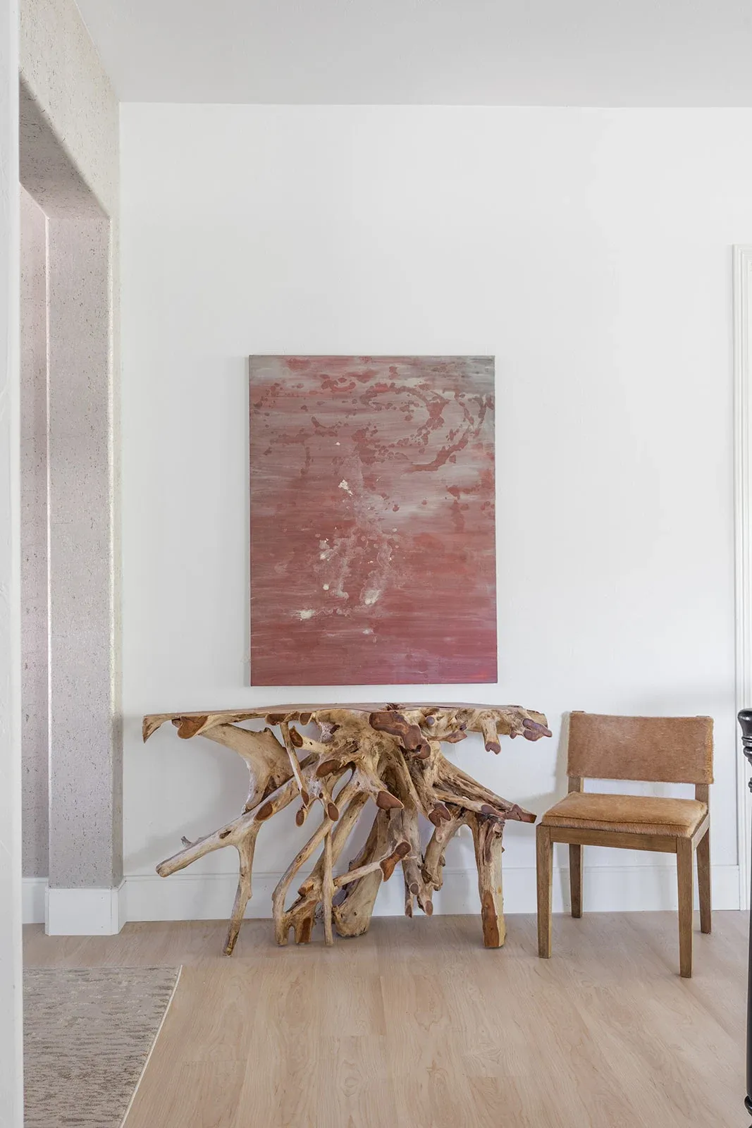 Large pink abstract painting above an upholstered chair in a light interior