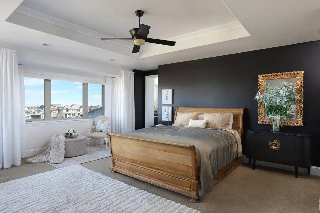 Bedroom with a wood bed, charcoal accent wall, original artwork, and panoramic windows