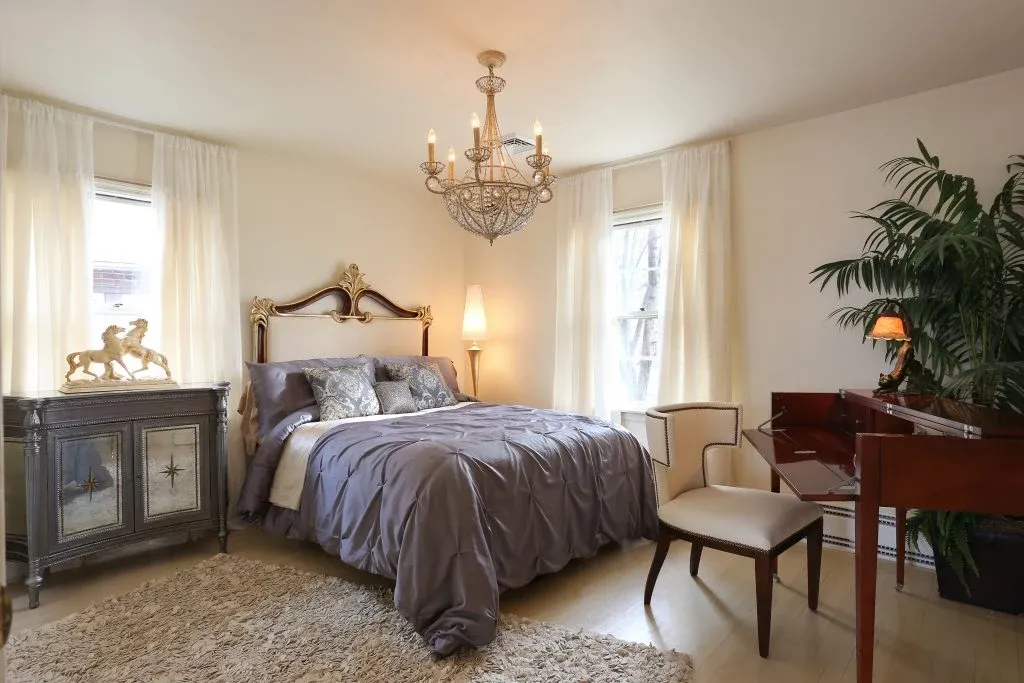 Traditional bedroom with a crystal chandelier, wood furnishings, and softly patterned textiles