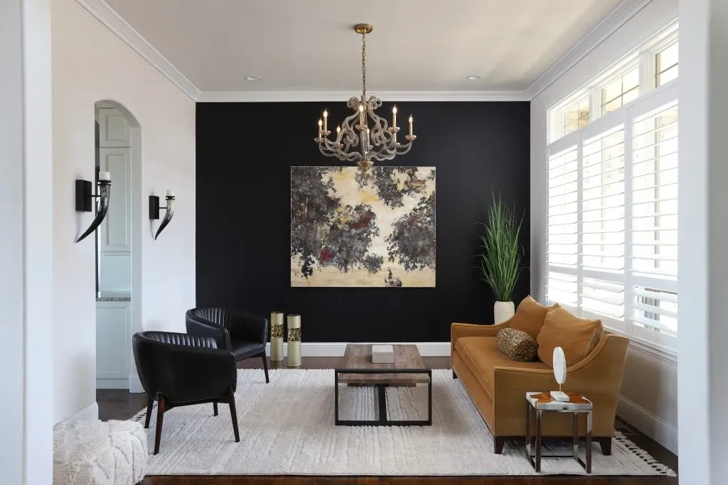 Dining room with a dark accent wall, original painting, chandelier, and gold chairs
