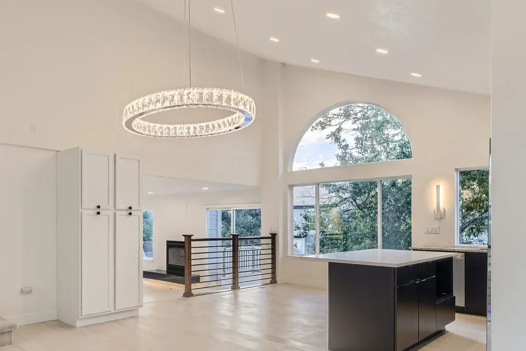 Open dining area with a vaulted ceiling, round chandelier, and arched window