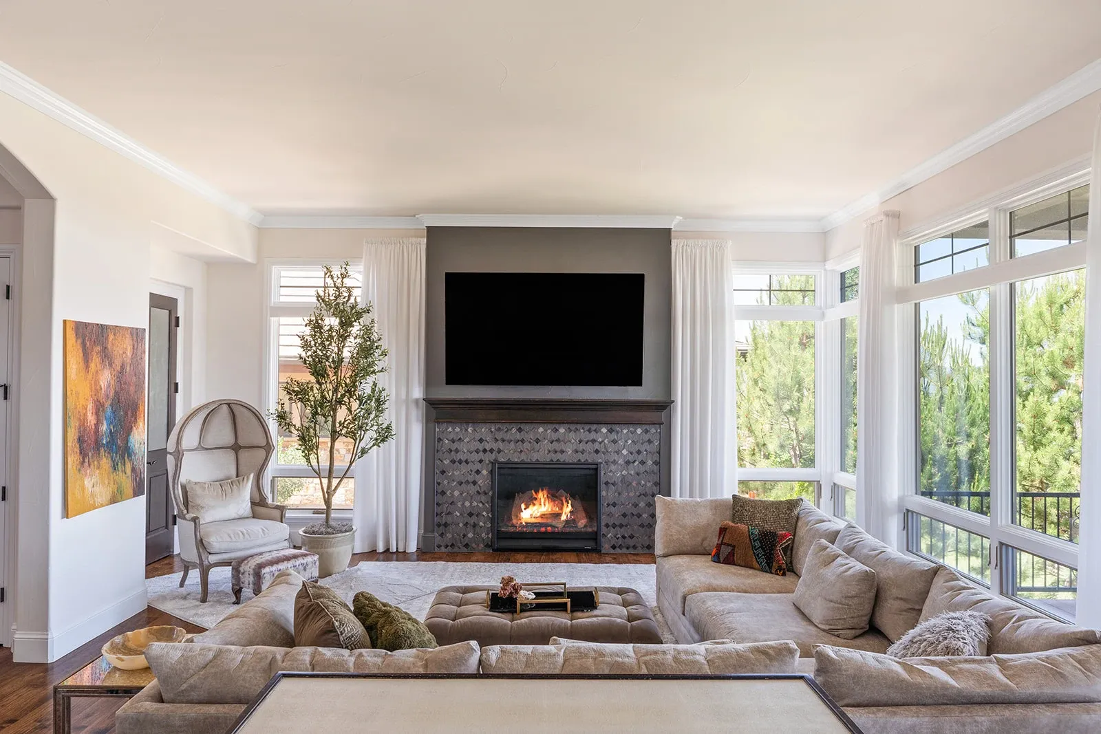 Light-filled living room with a marble fireplace, original artwork, and layered neutral furnishings