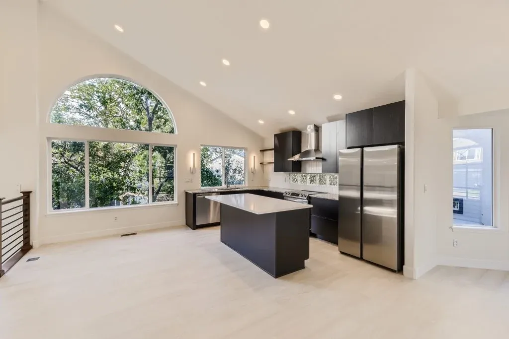 Open kitchen with a dark island, stainless appliances, and large arched windows