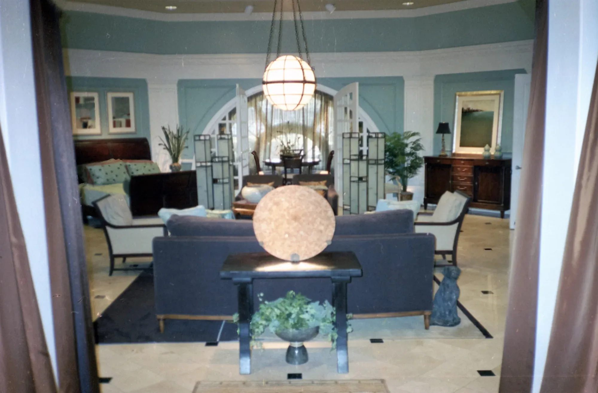 Blue-walled living room with dark upholstered seating and an arched entry