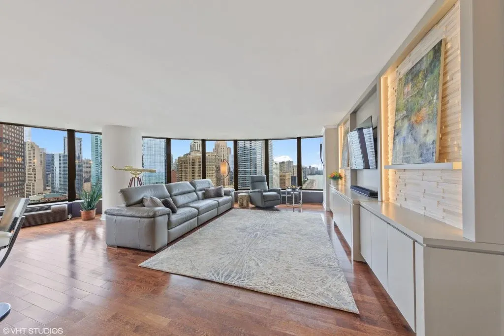 Spacious living room with wraparound windows, a sectional sofa, and lake views