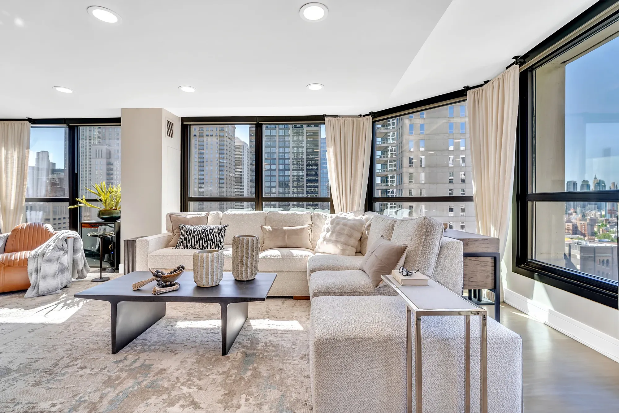 Contemporary living room with curved windows, cream seating, and city views