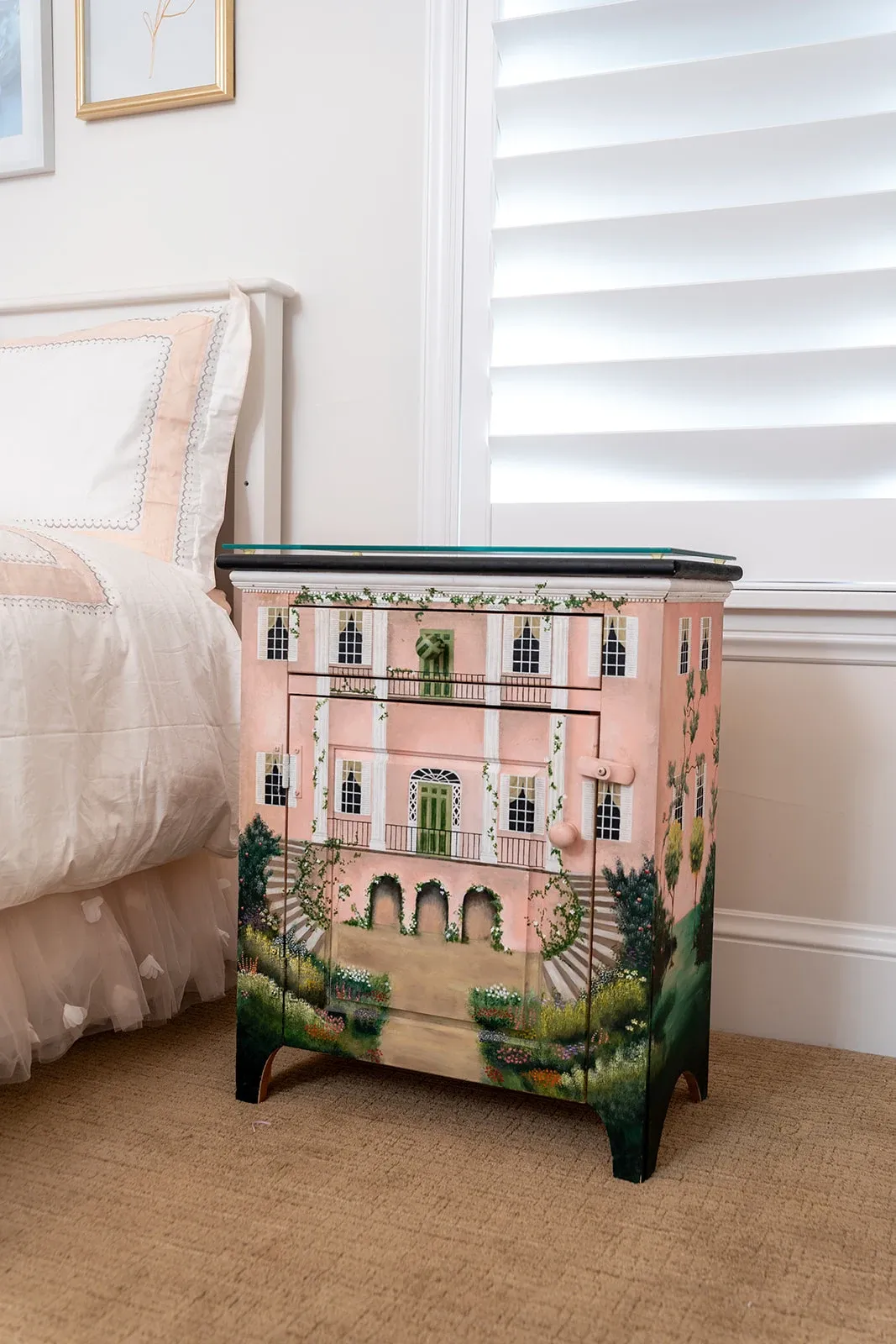 Decorative cabinet painted as an ornate pink building with windows and architectural details