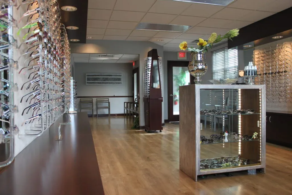 Optical boutique with wood flooring, display cases, and a curated eyewear wall